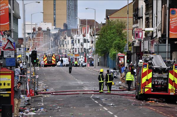 Croydon road looking like a tornado swept up it as fire tenders spray water twelve hours after the fires were set during riots in 2011.  - Sputnik International