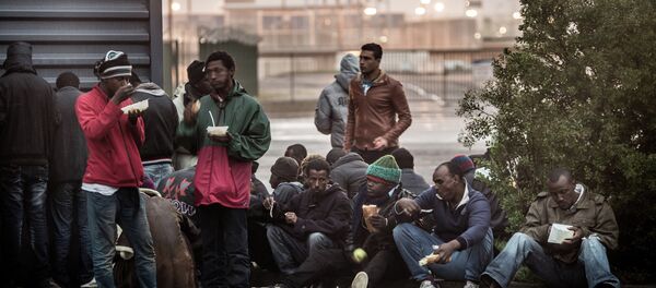 Migrants eat hot meals served by humanitarian organizations in the northeastern French port of Calais on October 29, 2014 - Sputnik International
