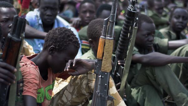 A file photo taken on February 10, 2015 shows young boys, child soldiers sitting on with their rifles - Sputnik International