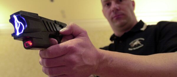 Clay Winn, of TASER International, demonstrates the company's Advanced M-26 model during a news conference in Las Vegas - Sputnik International