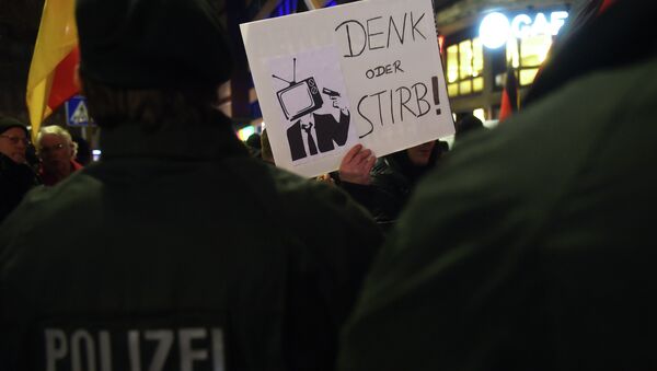 A sympathizer of Duegida, a local copycat of Dresden's right-wing populist movement PEGIDA (Patriotic Europeans Against the Islamisation of the Occident) holds up a placard reading 'Think or die!' in Duesseldorf, western Germany on February 2, 2015 - Sputnik International