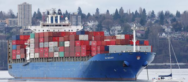 A sailboat moves past the 925-foot long HS Mozart cargo ship in Tacoma, Wash. File photo - Sputnik International