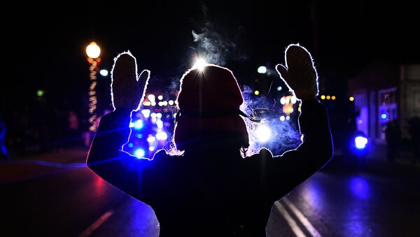 This November 25, 2014 file photo shows a protester holding up her hands in front of a police car in Ferguson - Sputnik International