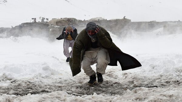Afghan survivors of an avalanche run to get relief goods distributed by an Afghan army helicopter in the Paryan district of Panjshir province, north of Kabul on March 1, 2015 - Sputnik International