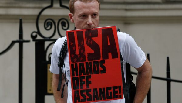 A supporter of WikiLeaks founder Julian Assange holds on to a placard with his teeth during a June vigil outside the Ecuadorian Embassy in London to mark Assange's two years in refuge at the embassy. - Sputnik International