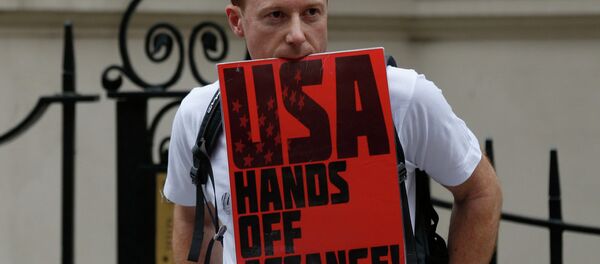 A supporter of WikiLeaks founder Julian Assange holds on to a placard with his teeth during a June vigil outside the Ecuadorian Embassy in London to mark Assange's two years in refuge at the embassy. - Sputnik International