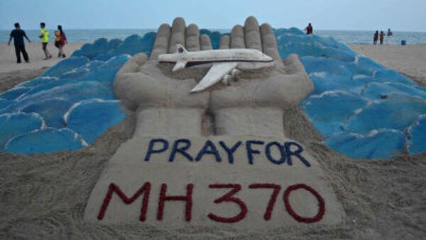 Beachgoers walk past a sand sculpture made by Indian sand artist Sudersan Pattnaik with a message of prayers for the missing Malaysian Airlines flight MH370 - Sputnik International