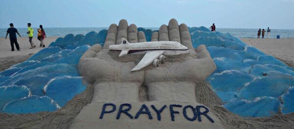 Beachgoers walk past a sand sculpture made by Indian sand artist Sudersan Pattnaik with a message of prayers for the missing Malaysian Airlines flight MH370 Beachgoers walk past a sand sculpture made by Indian sand artist Sudersan Pattnaik with a message of prayers for the missing Malaysian Airlines flight MH370 - Sputnik International