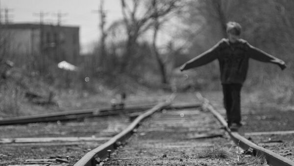 A boy balances on a train rail while walking along tracks - Sputnik International