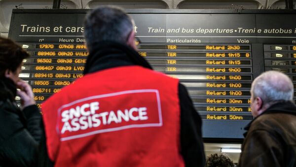 People stand next to a member of SNCF customer service staff in front of a board displaying departure information indicating that all trains have been delayed at Lyon-Part-Dieu railway station in Lyon - Sputnik International