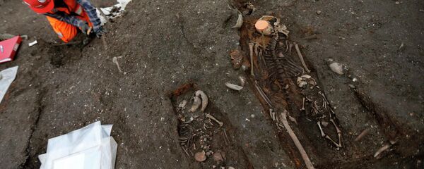 An archaeologist works near skeletons of a mother and two children found in the Bedlam burial ground on the future site of a Crossrail ticket hall next to Liverpool Street Station in London An archaeologist works near skeletons of a mother and two children found in the Bedlam burial ground on the future site of a Crossrail ticket hall next to Liverpool Street Station in London - Sputnik International