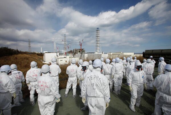 Members of the media wearing protective suits and masks report as they are escorted by TEPCO employees at Tokyo Electric Power Co. (TEPCO)'s tsunami-crippled Fukushima Daiichi nuclear power plant in Okuma, Fukushima prefecture on February 20, 2012. - Sputnik International