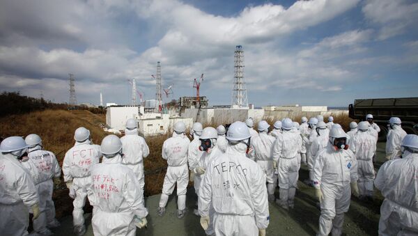 Members of the media wearing protective suits and masks report as they are escorted by TEPCO employees at Tokyo Electric Power Co. (TEPCO)'s tsunami-crippled Fukushima Daiichi nuclear power plant in Okuma, Fukushima prefecture on February 20, 2012 - Sputnik International