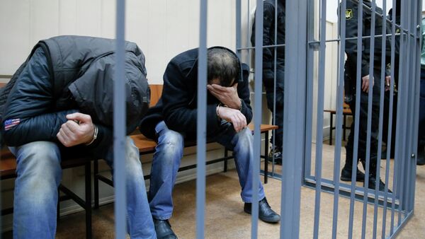 Shagid Gubashev (L) and Ramzan Bakhayev, detained over the killing of Russian opposition figure Boris Nemtsov, hide their faces inside a defendants' cage at a court building in Moscow March 8, 2015 - Sputnik International