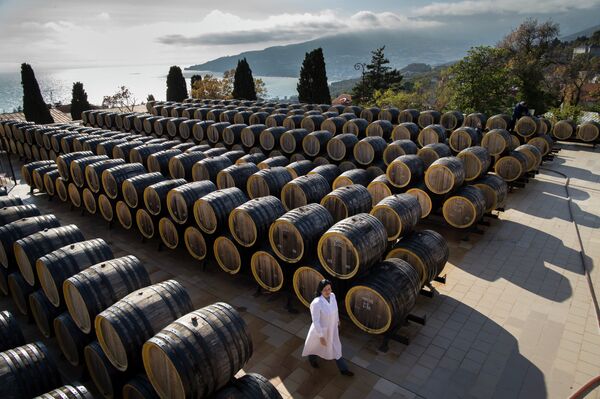 In this photo taken on Tuesday, Oct. 28, 2014, Rameta Kushkhova walks by barrels of wine in the state-owned Massandra winery in Yalta, Crimea In this photo taken on Tuesday, Oct. 28, 2014, Rameta Kushkhova walks by barrels of wine in the state-owned Massandra winery in Yalta, Crimea - Sputnik International