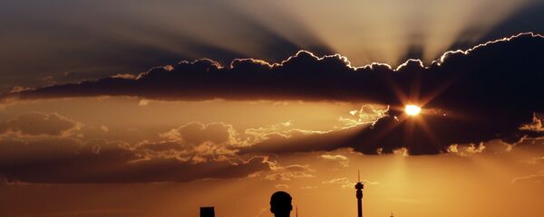 A man watches the sun set in as he overlooks the skyline in Johannesburg, South Africa - Sputnik International