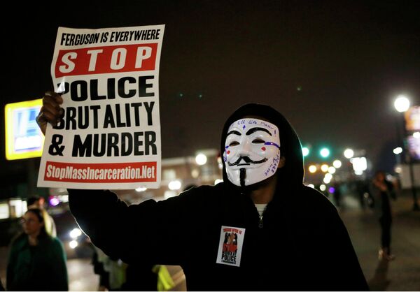 A protestor wearing a Guy Fawkes mask holds a sign as demonstrators march through the streets of Ferguson, Missouri, March 12, 2015 - Sputnik International