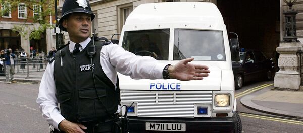 A policeman stops traffic as an armoured policevan leaves Bow street magistrates court in central London - Sputnik International