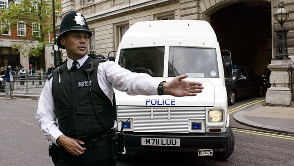 A policeman stops traffic as an armoured policevan leaves Bow street magistrates court in central London - Sputnik International