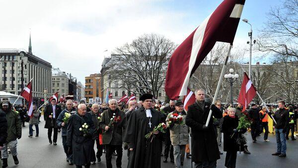 People carry Latvian flags as they march to the Freedom Monument to commemorate World War II veterans who fought in Waffen SS divisions, in Riga, Latvia, Sunday, March 16, 2014 - Sputnik International