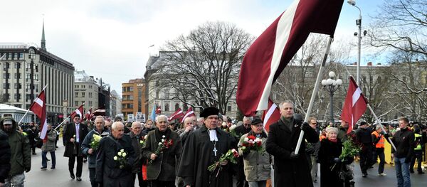 People carry Latvian flags as they march to the Freedom Monument to commemorate World War II veterans who fought in Waffen SS divisions, in Riga, Latvia, Sunday, March 16, 2014 - Sputnik International