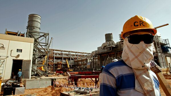 An Asian worker covers his face to protect it from the dust and the blazing sun at the site of Saudi Aramco's (the national oil company) Al-Khurais central oil processing facility under construction in the Saudi Arabian desert, 160 kms east of the capital Riyadh, on June 23, 2008 - Sputnik International