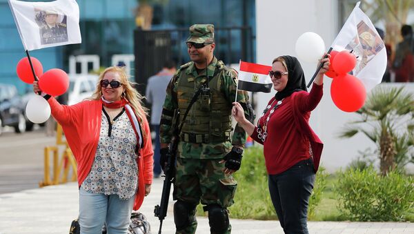 Egyptian women wave flags with pictures of Egyptian President Abdel Fattah al-Sisi, next to a soldier outside a conference centre hosting the Egypt Economic Development Conference (EEDC) in Sharm el-Sheikh, in the South Sinai governorate, south of Cairo, March 14, 2015 - Sputnik International
