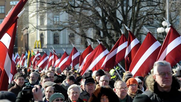 People carry Latvian flags at the march in Riga, Latvia - Sputnik International