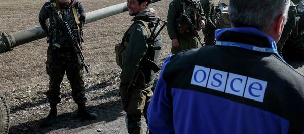 A member of Special Monitoring Mission of the Organization for Security and Cooperation (OSCE) to Ukraine walks along a convoy of Ukrainian armed forces in Blagodatne, eastern Ukraine A member of Special Monitoring Mission of the Organization for Security and Cooperation (OSCE) to Ukraine walks along a convoy of Ukrainian armed forces in Blagodatne, eastern Ukraine - Sputnik International