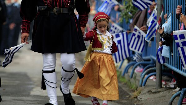 A girl dressed in a traditional costume holds the hand of a man in traditional military uniform during a parade, in the northern port city of Thessaloniki - Sputnik International