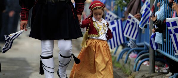 A girl dressed in a traditional costume holds the hand of a man in traditional military uniform during a parade, in the northern port city of Thessaloniki - Sputnik International