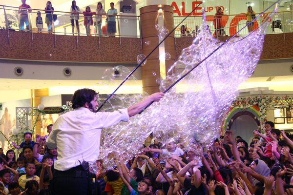 Sam Heath, otherwise known as Samsam Bubbleman charms the crowd with a net of bubbles at a supermarket during one of his Bubbleology shows. - Sputnik International