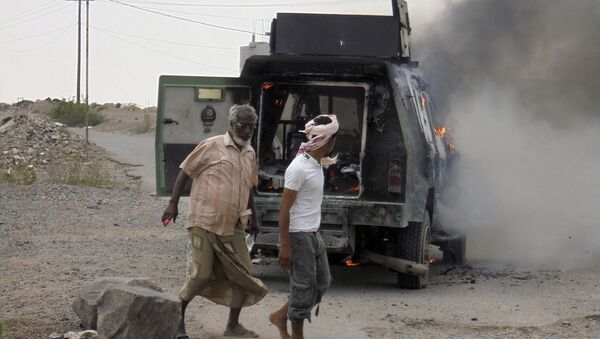 People walk by a police armoured personnel carrier attacked by militants in Lahej near Yemen's southern port city of Aden - Sputnik International