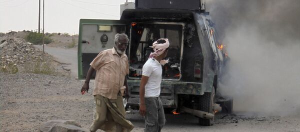 People walk by a police armoured personnel carrier attacked by militants in Lahej near Yemen's southern port city of Aden People walk by a police armoured personnel carrier attacked by militants in Lahej near Yemen's southern port city of Aden - Sputnik International