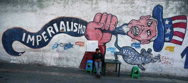 A man sits next to graffti, which reads imperialism and traitor, in Caracas March 9, 2015 - Sputnik International