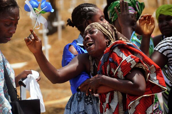 Relatives weep as they bury a loved one suspected of dying from the Ebola virus at a new graveyard on the outskirts of Monrovia, Liberia, March 11, 2015 - Sputnik International
