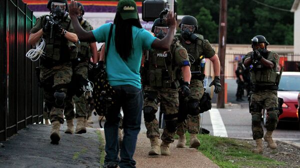In this Aug. 11, 2014, file photo, police wearing riot gear walk toward a man with his hands raised Monday, Aug. 11, 2014, in Ferguson - Sputnik International