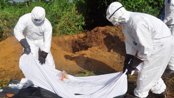 Health workers prepare to place the body of a man who was suspected of dying from the Ebola virus into a grave on the outskirts of Monrovia, Liberia - Sputnik International