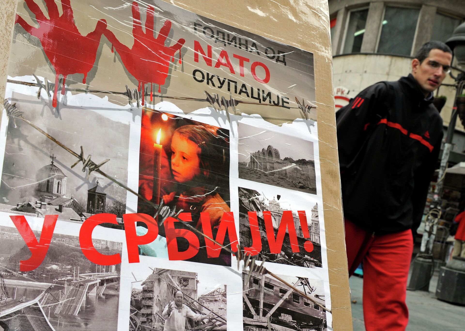 A man walks past a poster with the reading “Ten years of NATO occupation of Serbia”, and displaying images from 1999 NATO air campaign against Serbia and Montenegro, in Belgrade on March 23, 2009.  - Sputnik International, 1920, 24.03.2022
