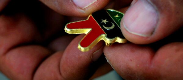 A Libyan man holds a souvenir of the Libyan revolution in the colors of the pre-Gadhafi flag A Libyan man holds a souvenir of the Libyan revolution in the colors of the pre-Gadhafi flag - Sputnik International