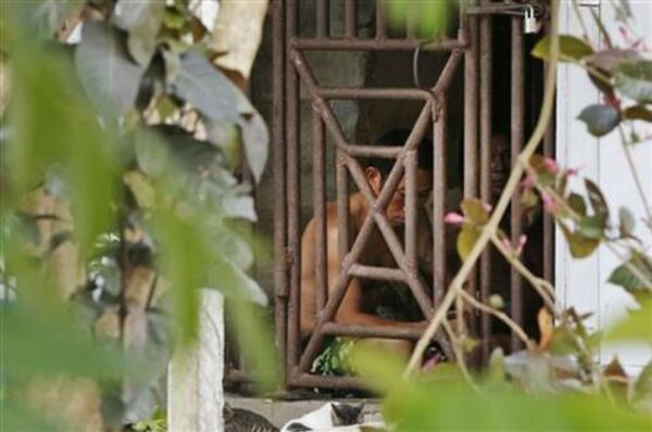 Thai and Burmese fishing boat workers sit behind bars inside a cell at the compound of a fishing company in Benjina, Indonesia. Thai and Burmese fishing boat workers sit behind bars inside a cell at the compound of a fishing company in Benjina, Indonesia. - Sputnik International