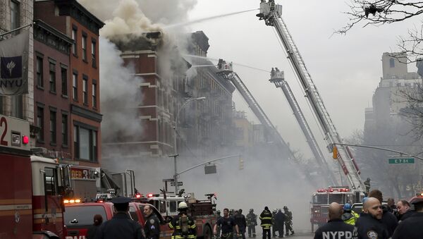 New York City Fire Department and Police stand by as firefighters fight a fire near where a residential apartment building collapsed and was engulfed in flames in New York City's East Village neighborhood - Sputnik International