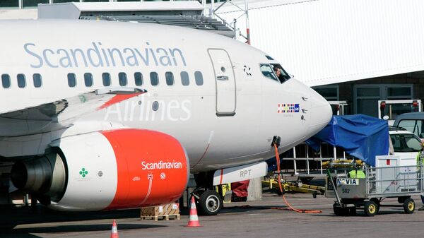 The pilot of an SAS Boeing 737 series jets speaks to his ground staff through the cockpit window at the gate of Terminal 4 on Arlanda airport in Stockholm, Sweden. File photo - Sputnik International