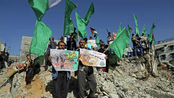 Palestinian Hamas supporters wave Hamas flags during a protest against the decision by the U.N. Relief and Works Agency to suspended an aid program for Gaza residents displaced by the last summer's war, in Beit Hanoun, northern Gaza. File photo - Sputnik International