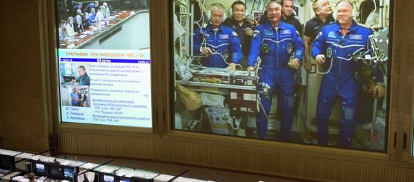 This view from Russian Mission Control Center shows live television of the Expedition 39 crew members gathered together on the International Space Station. - Sputnik International