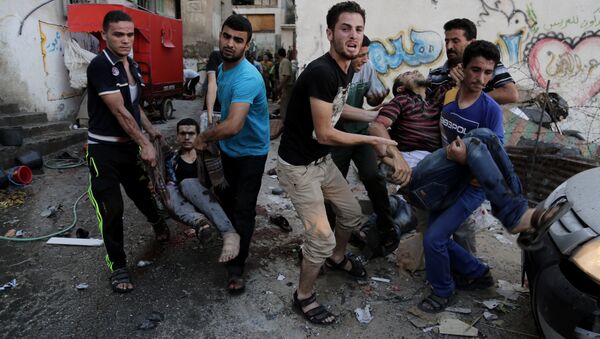 Palestinians help carry injured men following an Israeli Strike in Shijaiyah neighborhood, eastern Gaza City, last July. - Sputnik International