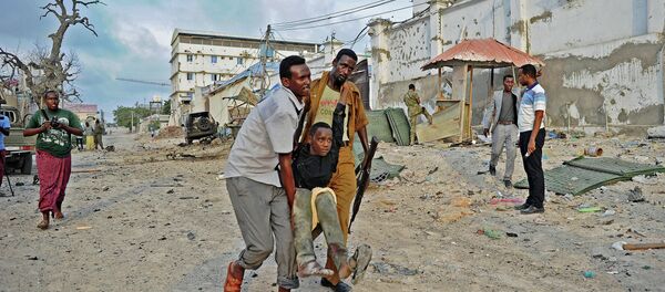 An injured youth is carried away from the scene of a car bomb attack and armed raid by Al Shebab militants on the Maka al Mukarama hotel in Mogadishu on March 27, 2015 - Sputnik International