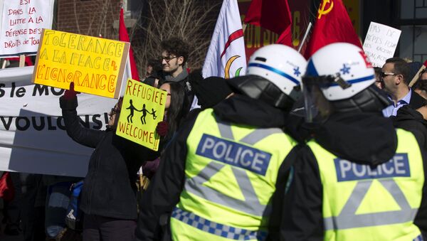 Police watch as a group of people rally to denounce a planned march by the Patriotic Europeans Against the Islamization of the West (PEGIDA) in Montreal March 28, 2015 - Sputnik International