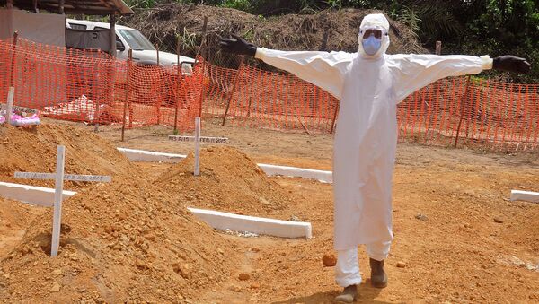 A health worker holds up his arms after he and others buried a person that they suspect died form the Ebola virus at a new graveyard on the outskirts of Monrovia, Liberia - Sputnik International
