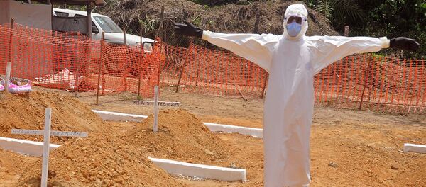 A health worker holds up his arms after he and others buried a person that they suspect died form the Ebola virus at a new graveyard on the outskirts of Monrovia, Liberia A health worker holds up his arms after he and others buried a person that they suspect died form the Ebola virus at a new graveyard on the outskirts of Monrovia, Liberia - Sputnik International